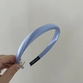 Detalle de la diadema de satén azul claro con textura suave y la etiqueta artesanal - Azul