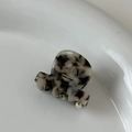 Détail d'une mini pince à cheveux en acétate avec texture marbrée sur assiette blanche - Tortoise