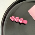 Close-up of a pink resin hair clip with three heart shapes on a black plate - Pink White Heart-Dark Pink