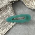 Detailed close-up of light green acetic acid hair clip with wavy edges and hollow water drop - Green