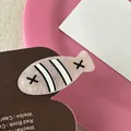 Detailopname van de visvormige haarspeld met crème marmertextuur en zwarte accenten - Anemoonvis