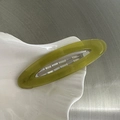 Dettaglio ravvicinato di un fermaglio per capelli ovale in resina verde oliva su piatto - Verde