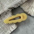 Detailed macro view of yellow wavy acetate hair clip with golden metal spring clip - Yellow