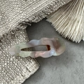 Close-up of wavy acetate hair clip with marble textures and golden metal duckbill base - AB Color