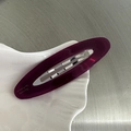 Dettaglio di un fermaglio ovale in resina viola con clip in metallo e finitura semitrasparente - Borgogna