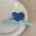 Detail shot of a matte blue heart-shaped hair claw clip on a white ceramic tray - Heart-shaped Color Scheme - Blue