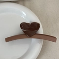 Detail view of a chocolate brown heart-shaped hair claw clip on a white ceramic plate - Heart-shaped Color Scheme - Brown