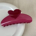 Close-up of a glossy rose pink heart claw clip on a white ceramic plate with fabric - Heart-shaped Color-blocked Fan - Rose Red