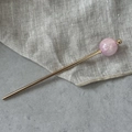 Detail van elegante gouden haarpin met een roze marmeren kraal en gouden accenten - Roze