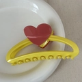 Detail of yellow heart hair claw clip on white ceramic plate with soft natural lighting - Heart-shaped Color-blocked Clothes Hanger - Yellow