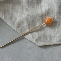 Detailopname van een gouden haarpincet met rode gemarmerde bol en gladde afwerking - Oranje