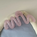 Vue détaillée de dessus d'une pince à cheveux rose translucide en résine ondulée avec ressort - Rose transparent