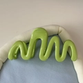 Vue détaillée de la pince à cheveux ondulée vert vif avec une finition brillante moderne - Vert