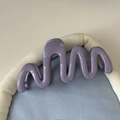 Détail macro d'une pince à cheveux ondulée lavande sur un fond en tissu doux et élégant - Violet