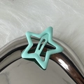 Detail shot of a Y2K mint green star-shaped hair clip with a matte finish on fur background - Green