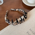 Cerchietto leopardato elegante con borchie nere e strass su sfondo in legno scuro - Caffè Chiaro