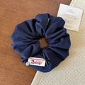 Détail du chouchou bleu foncé avec étiquette vintage, nœud noir et bouton argenté - Bleu marine