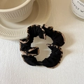 Détail d'un chouchou noir avec bordure léopard et perle brillante sur fond de table blanche - Noir Avec Bordure Léopard