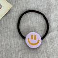 Elastic hair tie featuring a light purple round resin charm with a yellow smiley face design - Purple