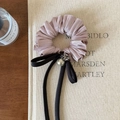 Close-up of pink satin hair scrunchie with long black ribbon and large pearl detail - Pink