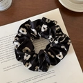 Macro shot of black and white floral satin scrunchie detail with silk texture - Black Printed