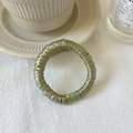 Sage green seamless silk scrunchie on textured fabric with elegant home decor - Green