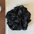 Detailed view of black paisley print fabric scrunchie on a decorative book surface - Four Layers Black Floral