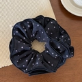 Dettaglio di un elastico per capelli nero a pois viola su un tappetino intrecciato - Pois Blu Notte