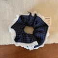 Primer plano de coletero de cuadros azul marino con encaje sobre un mantel tejido - Encaje a Cuadros Azul Marino