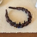 Dettaglio del cerchietto in tessuto a scacchi con treccia e ciondolo a stella dorata - Bottone Caffè (Scozzese)