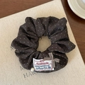 Dettaglio di un elastico per capelli marrone a pois con etichetta e perla - Pois Caffè / caffè