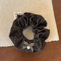 Dettaglio dell'elastico a pois con un piccolo fiocco e una perla su un tappeto - Marrone Scuro Retrò / Pois Caffè