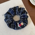 Detailansicht eines blauen Karo-Haargummis mit roten und gravierten Knöpfen auf Tisch - Marineblau Knopf Haargummi