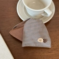 Detalle de pinza para pelo vintage a cuadros con botón Faith & Hope sobre mesa de madera - Cuadros Café Contraste