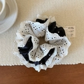 Detail van witte kanten scrunchie met zwarte polkadots op een geweven ondergrond - Zwarte Kant