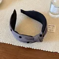 Dettaglio di un cerchietto in tessuto grigio a pois neri con un nodo centrale intrecciato - Grigio chiaro