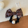 Dettaglio dell'elastico per capelli scozzese marrone con logo dorato e grande perla bianca - Caffè Quadri