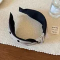 Dettaglio di un cerchietto annodato con motivo a pois e design bicolore in tessuto grigio e nero - Beige