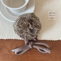 Detail of mocha brown knit hollow rose hair tie with ribbon on a cozy wooden table - Champagne