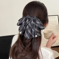 Dettaglio del fiocco a scacchi con perle bianche indossato su una coda di cavallo - Set Fermagli Plaid Nero