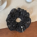 Close-up of hollow knit scrunchie with tweed texture and elegant pearl pin detail - Black