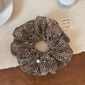 Detail of coffee brown mesh knit scrunchie with pearl and gold metal charm on a rustic desk - Champagne