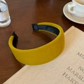 Primer plano de diadema acolchada de terciopelo amarillo mostaza sobre un libro antiguo - Amarillo Jengibre
