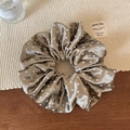 Gros plan d'un chouchou en satin de soie marron à pois blancs sur un support tissé - Marron