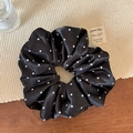 Détail d'un chouchou en satin noir à pois sur un set de table tressé esthétique - Noir
