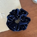 Detailweergave van donkerblauwe fluwelen scrunchie met witte stippen op zachte stof - Blauw Stippen Fluweel