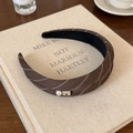 Dettaglio di un cerchietto a coste marrone caffè con perla e strass su un libro - Cerchietto a Righe / Strisce marroni