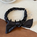 Detail view of black satin bow headband showing non-slip inner teeth and woven texture - Black