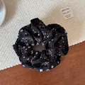 Primer plano de coletero negro con flores de estilo vintage sobre superficie textil - Coletero de Doble Capa
