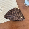 Dettaglio molletta per capelli leopardata con stemma dorato su sfondo in legno scuro - Stampa Leopardata Scura